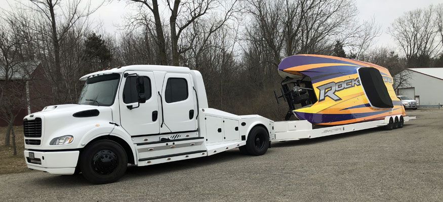 A custom semi truck hauling a car that is sideways.
